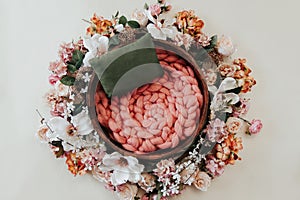 Newborn photography background - floral wreath on white background with wooden bowl and pink knitted chunky blanket knitted center