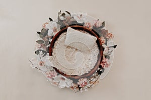Newborn photography background - floral wreath on white background with wooden bowl and white knitted center. Newborn girl