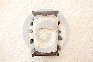 Newborn photography background - rustic wooden bed  with white chunky blanket, knitted pillow on white fluffly backgdrop