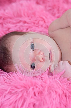 Newborn portrait, baby girl lying on pink background