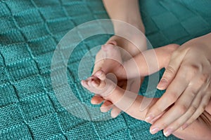 Newborn`s legs in hands of mother.