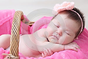 Newborn sleeping in basket, baby girl lying in pink blanket, cute child