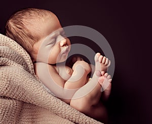 Newborn sleeping on Blanket over black background. Baby sleep in Fetal position Side view. Infant Development. One month Child photo