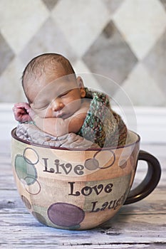 Newborn sleeping in giant coffee cup