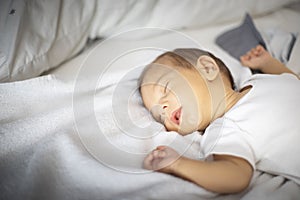 Newborn sleeping lying on his back, on white and grey bedding