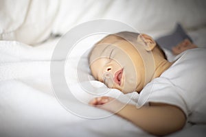 Newborn sleeping lying on his back, on white and grey bedding. Top view