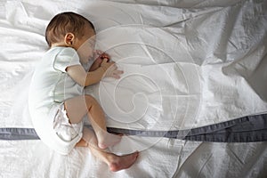 Newborn sleeping in parents bed, lying on side. Copy space