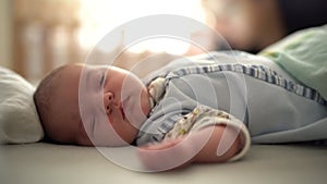 Newborn sleeps on the bed and smiles in his sleep