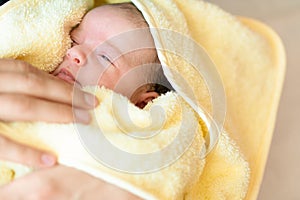 Newborn after taking a bath. Little baby wrapped in towel