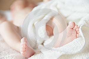 Newborn tiny baby lying on the bed with blanket