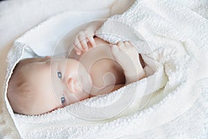 Newborn tiny baby lying on the bed side view