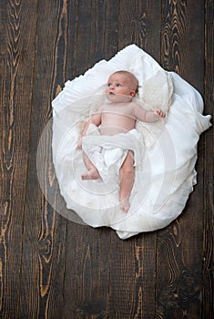 Newborn toddler with blue curious eyes on wooden background