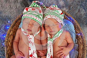 Newborn twin baby boys sleeping in a basket