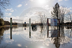 Flooded roadway with No Fly Tipping sign and car wheel submerged in water. Environmental concept global warming climate change