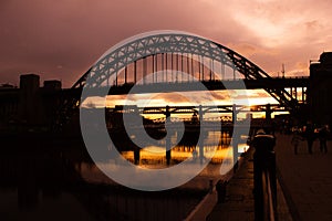 Tyne bridge at sunset in silhouette with reflection on River