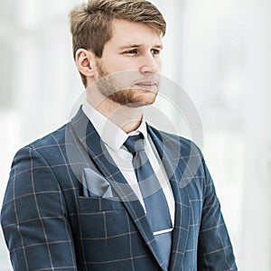 Newcomer businessman in a business suit stands near the window