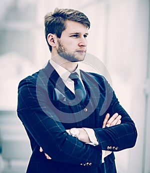 Newcomer businessman in a business suit stands near the window,