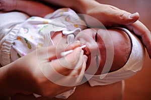 A newly born baby. The first days of life. Happy baby and mom at home. Feeding, wiping, hygienic procedures