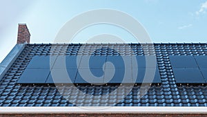 Newly build house in the Netherlands with solar panels attached on the roof against a sunny sky Close up of new building