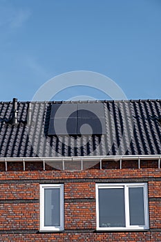 Newly build houses with solar panels attached on the roof against a sunny sky Close up of new building with black solar