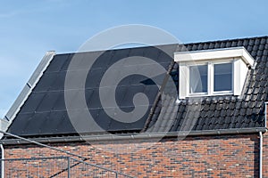 Newly build houses with solar panels attached on the roof against a sunny sky Close up of new building with black solar