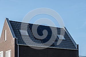 Newly build houses with solar panels attached on the roof against a sunny sky Close up of new building with black solar