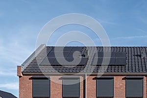 Newly build houses with solar panels attached on the roof against a sunny sky Close up of new building with black solar