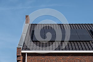 Newly build houses with solar panels attached on the roof against a sunny sky Close up of new building with black solar