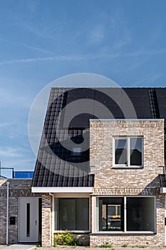 Newly build houses with solar panels attached on the roof against a sunny sky Close up of new building with black solar