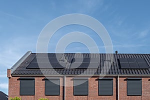 Newly build houses with solar panels attached on the roof against a sunny sky Close up of new building with black solar