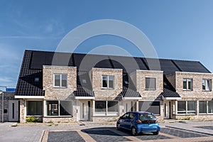 Newly build houses with solar panels attached on the roof against a sunny sky Close up of new building with black solar