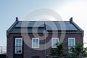 Newly build houses with solar panels attached on the roof against a sunny sky Close up of new building with black solar