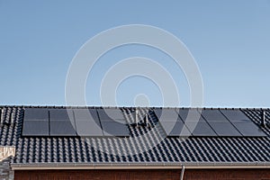 Newly build houses with solar panels attached on the roof against a sunny sky Close up of new building with black solar