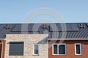 Newly build houses with solar panels attached on the roof against a sunny sky Close up of new building with black solar