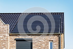 Newly build houses with solar panels attached on the roof against a sunny sky Close up of new building with black solar