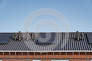 Newly build houses with solar panels attached on the roof against a sunny sky Close up of new building with black solar