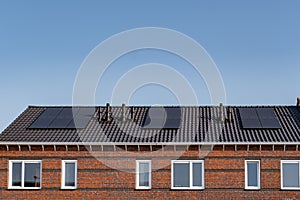 Newly build houses with solar panels attached on the roof against a sunny sky Close up of new building with black solar