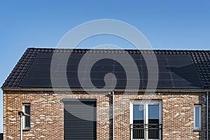 Newly build houses with solar panels attached on the roof against a sunny sky Close up of new building with black solar