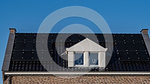 Newly build houses with solar panels attached on the roof against a sunny sky Close up of new building with black solar