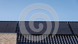 Newly build houses with solar panels attached on the roof against a sunny sky Close up of new building with black solar