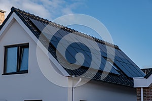 Newly build houses with solar panels attached on the roof against a sunny sky Close up of new building with black solar