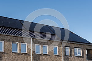 Newly build houses with solar panels attached on the roof against a sunny sky Close up of new building with black solar