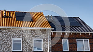 Newly build houses with solar panels attached on the roof against a sunny sky Close up of new building with black solar