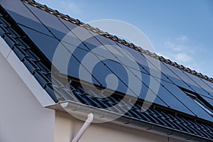 Newly build houses with solar panels attached on the roof against a sunny sky Close up of new building with black solar