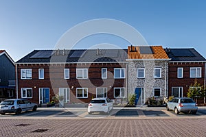 Newly build houses with solar panels attached on the roof against a sunny sky Close up of new building with black solar