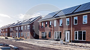 Newly build houses with solar panels attached on the roof against a sunny sky, housing market
