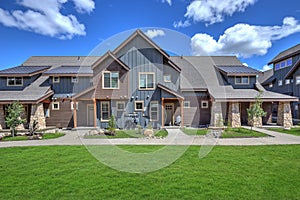 Newly build modern and rustic home from exterior in natural brown and grey colors with walkways, green grass and natural stone