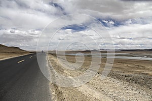 The newly built asphalt road is flanked by yellow, deserted and inhabited prairie