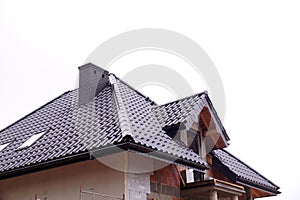 A newly built residential house. A fragment of the roof made of ceramic roof tiles. New chimneys and roof windows