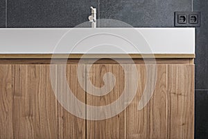 Newly installed designer bathroom with tall wooden cabinet with drawers, one-piece white porcelain